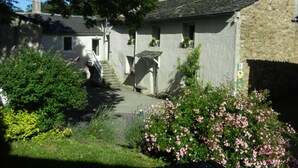 Un edificio de piedra con una escalera que lleva a una puerta, rodeado de follaje y flores.