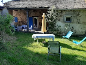 Un espace extérieur aménagé dans un style rustique, avec une table, des chaises et un parasol.