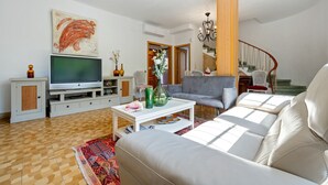 A living room with a sofa, TV, and decorative items. - Chalet '50 M to the Beach' with Private Terrace, Wi-Fi and Air Conditioning (Comarruga)