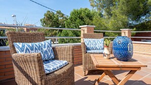 Wicker furniture with patterned cushions, a wooden table, and decorative vases on an outdoor patio. - Chalet '50 M to the Beach' with Private Terrace, Wi-Fi and Air Conditioning (Comarruga)