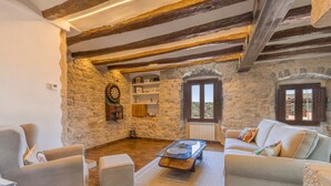 A rustic room with exposed wooden beams, stone walls, a sofa, a coffee table, and a dartboard. - Stone House with Private Spa and Unique Jacuzzi (Nalec)
