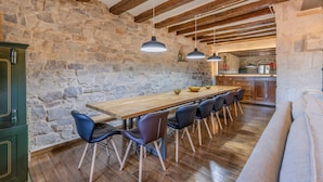 A rustic interior with exposed stone walls, wooden beams, a long wooden table with chairs, and a sofa. - Stone House with Private Spa and Unique Jacuzzi (Nalec)