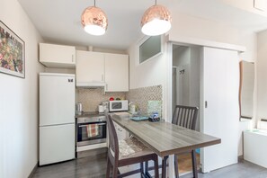 A compact kitchen with white cabinets, a microwave, a stove, and a dining table with chairs.