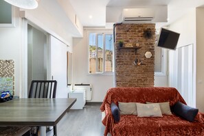 A modern living room with a sofa, a dining table, and a kitchen area. - Apartment 'Studio Near Park Güell' with Wi-Fi and Air Conditioning (Barcelona)
