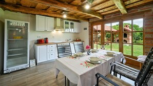 A rustic kitchen with wooden beams, a refrigerator, and a dining area with a table set for two. - 2 bedroom cozy home in Konjscina (Konjscina)