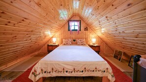 A cozy attic bedroom with a sloped ceiling, a single bed with floral bedding, two bedside lamps, and a small window with checkered curtains. - 2 bedroom cozy home in Konjscina (Konjscina)