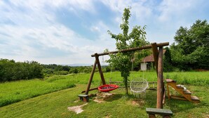 A wooden swing set in a grassy area with a small table and chairs nearby. - 2 bedroom cozy home in Konjscina (Konjscina)