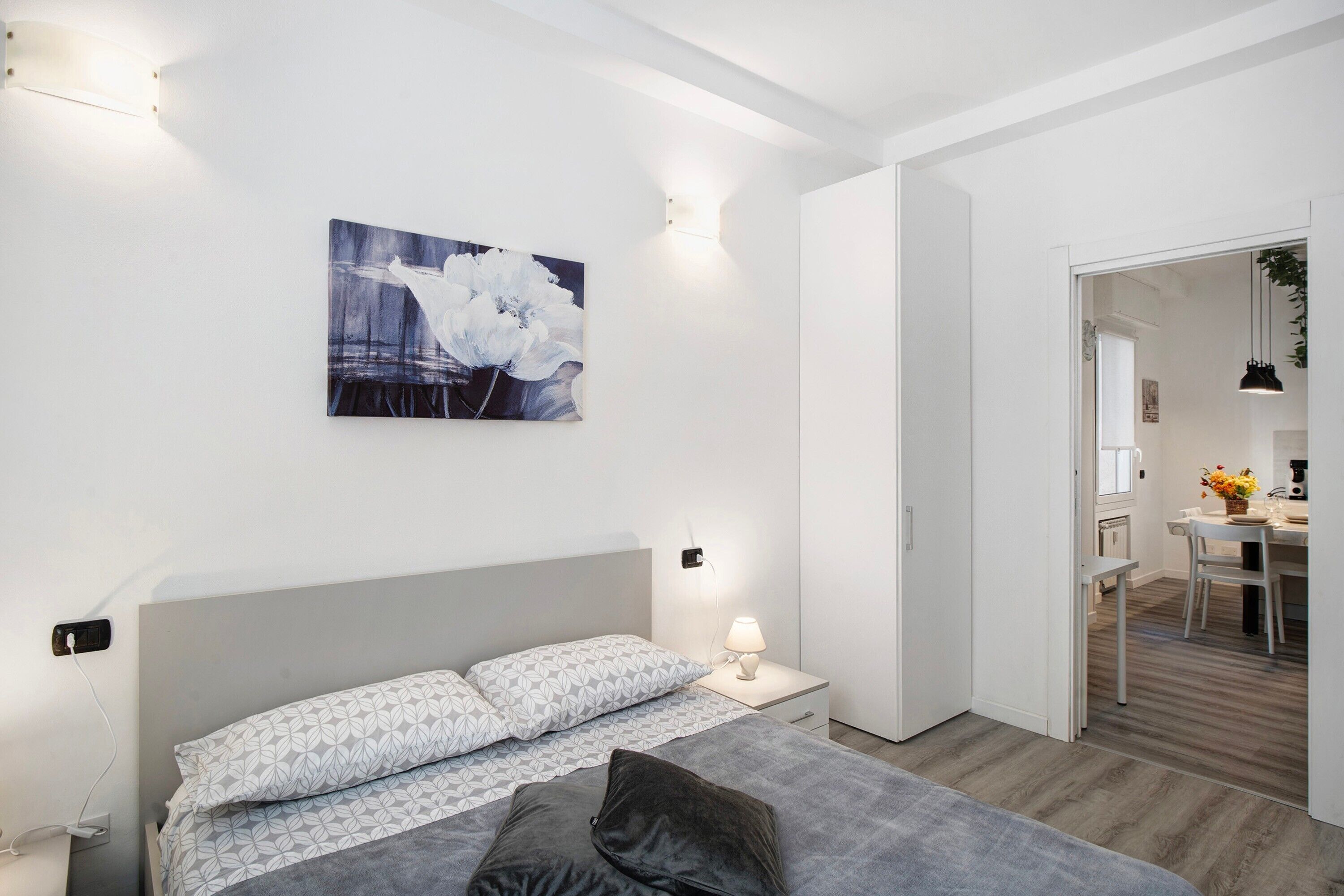A modern bedroom with a bed, bedside lamp, and a painting on the wall.
