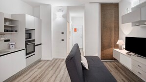 Eine kompakte Küche mit modernen Geräten, ein Sofa und ein Fernseher in einer kleinen Wohnbereitschaft.