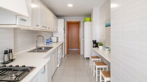 Una cocina moderna con armarios blancos, estufa, lavabo y puerta de madera.