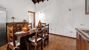 Un coin repas avec une table en bois, des chaises et un grand vase.
