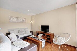 Un salon comprenant un canapé, une table basse, un meuble pour la télévision et un fauteuil.