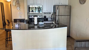 Una cocina moderna con armarios blancos, electrodomésticos de acero inoxidable y una isla central.