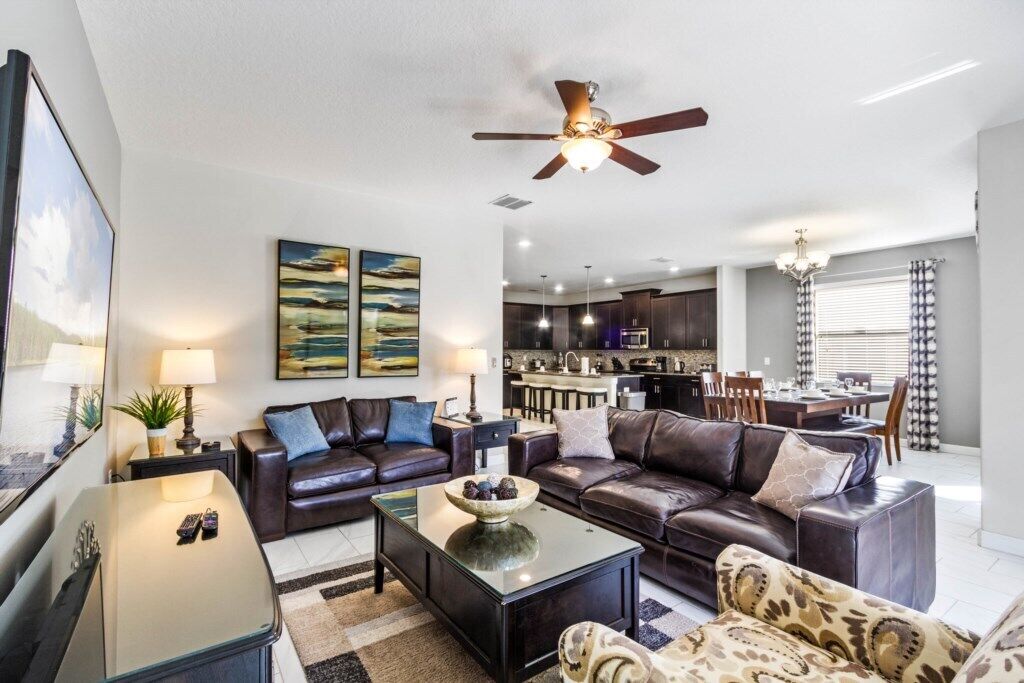 A modern living room with leather sofas, a glass coffee table, and artwork on the walls.