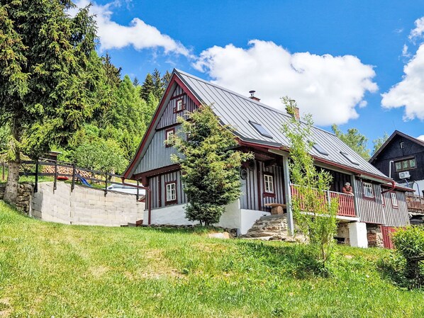 A traditional wooden house with a steeply pitched roof, a stone foundation, and a small porch. - Jizerka by Interhome (Tanvald)
