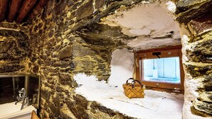 A rustic stone interior with a wooden table, a bathtub, and a window with a view. - Jizerka by Interhome (Tanvald)