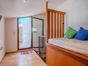 A room with a bed, a wooden partition, a sliding glass door, and a colorful rug.