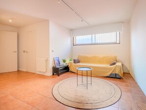 Ein Zimmer mit einer Couch, einem kleinen Tisch, einer Heizung und einem Fenster.