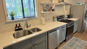 Uma cozinha moderna com eletrodomésticos de aço inoxidável, uma pia dupla e uma janela com vista para árvores.