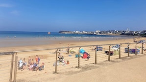 A beach with a clear sky, a sandy shore, and a distant cityscape. - Central Portrush Penthouse Retreat (Portrush)
