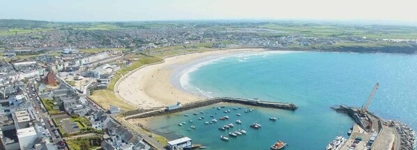 Overlooking a sheltered bay with anchored boats, this coastal town offers a tranquil waterfront setting.