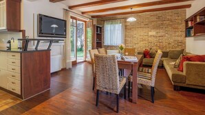 A spacious living area with a wooden dining table, wicker chairs, a sofa, and a television in the corner. - Wonderful  villa for 9 guests with A/C, WIFI, TV, terrace and pets allowed (Balatonfüred)