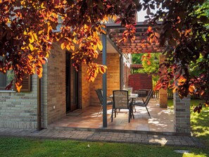 Une terrasse avec des sièges d’extérieur, des murs en briques et une pergola.