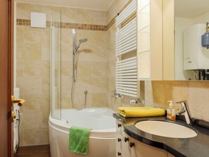 Un baño con bañera, ducha, lavabo y espejo.