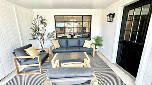 Una sala de estar moderna con un sofá, sillones y una mesa de centro. Se ve una ventana grande con vistas al exterior.