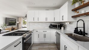 Una cocina moderna con armarios blancos, un lavamanos de acero inoxidable y un horno empotrado.