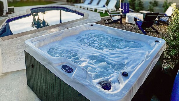 Un jacuzzi con vistas a una piscina y sillas de descanso.