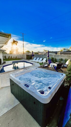 Uma banheira de hidromassagem com vista para uma piscina e espreguiçadeiras.