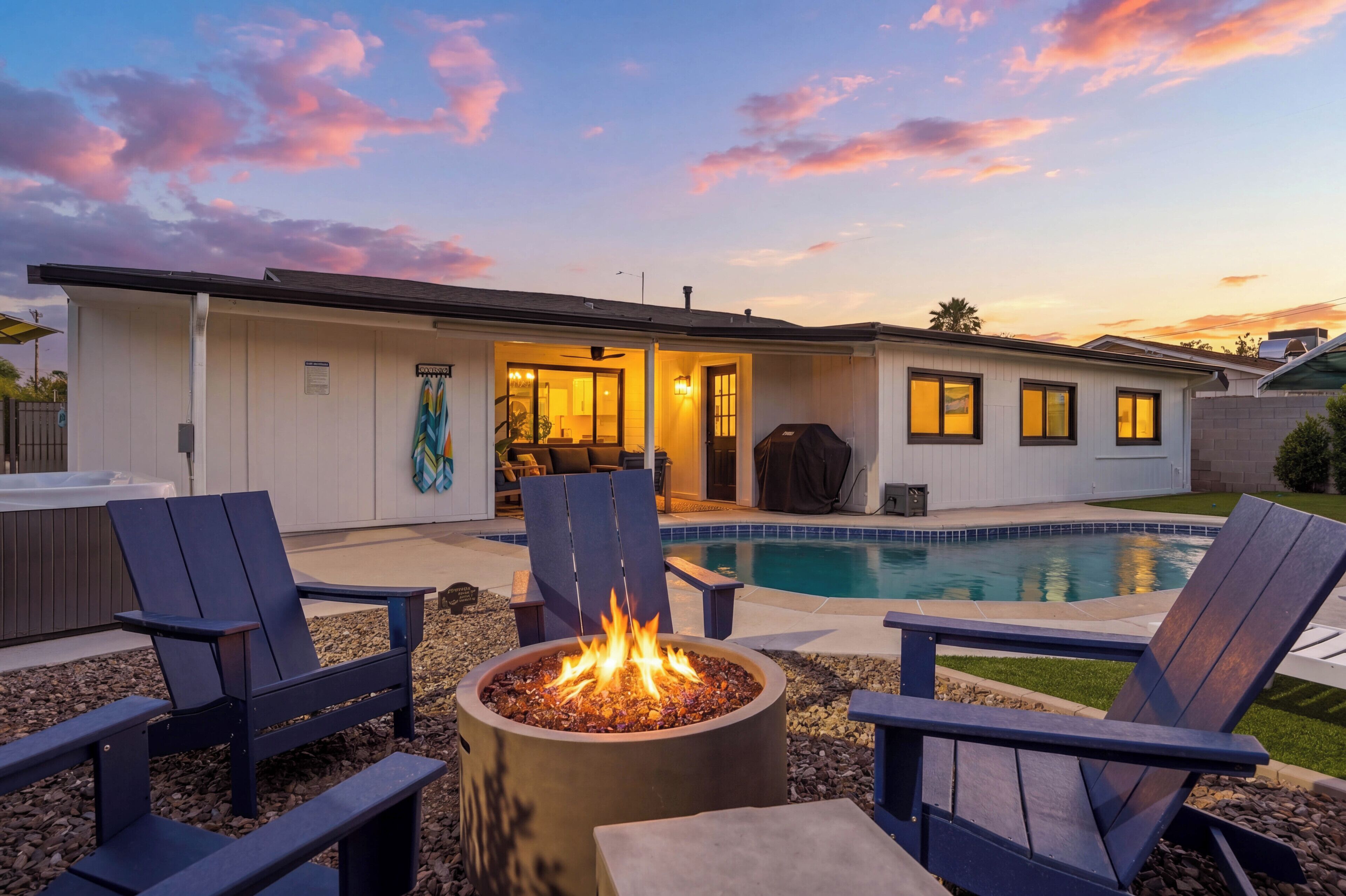 A modern house with a swimming pool, outdoor seating, and a fire pit.