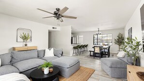 Una sala de estar moderna con un sofá modular, una mesa de centro y un comedor con sillas y una mesa.
