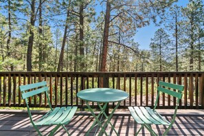 A wooden deck with a green table and two green chairs, surrounded by tall pine trees. - A/C, Views, Newly Renovated, Peaceful Retreat! (Durango)
