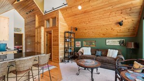 A cozy interior with a wooden ceiling, a living area with a sofa and chairs, a dining area with a bar, and a kitchen visible in the background. - A/C, Views, Newly Renovated, Peaceful Retreat! (Durango)