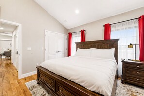 A bedroom with a large bed, a wooden dresser, a desk with a lamp, and a view of the city through the window. - Private 1BR Apt, 2BD 1BA, Sleeps 5, Clean & Reliable, Near NYC (Scotch Plains)