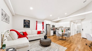 A modern living room with a sofa, coffee table, and dining area.