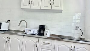 Eine Küche mit weißen Schränken, einer Edelstahl-Spüle, einer Mikrowelle, einer Kaffeemaschine und einem Toaster.