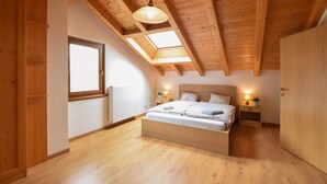 Une chambre avec un plafond en bois, un lit, des tables de chevet avec des lampes et une fenêtre.
