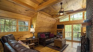 A cozy cabin interior with a wooden ceiling, leather sofa, and a fireplace. - Cabin in the mountains with hot tub! (Ellijay)