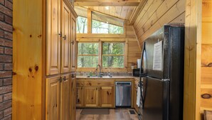 A wooden cabin kitchen with a brick wall, wooden cabinets, a refrigerator, and a sink. - Cabin in the mountains with hot tub! (Ellijay)