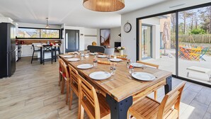 A modern kitchen with a dining area, large windows, and a view of the outdoors.