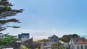 A coastal residential area with houses, a beach, and a clear sky.
