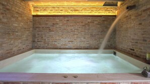 A brick-walled room with a large, rectangular hot tub. - Beautiful apartment for 2 guests with hot tub, pool, A/C, WIFI, TV, patio and pets allowed (Montecatini Terme)