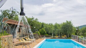 A swimming pool with a water feature, surrounded by lounge chairs and a stone wall. - Beautiful apartment for 2 guests with hot tub, pool, A/C, WIFI, TV, patio and pets allowed (Montecatini Terme)