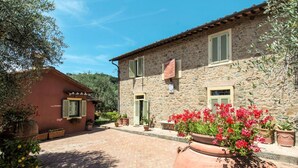 A stone building with a courtyard, potted plants, and a large terracotta pot with red flowers. - Beautiful apartment for 2 guests with hot tub, pool, A/C, WIFI, TV, patio and pets allowed (Montecatini Terme)