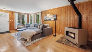 A cozy living room with a sofa, a fireplace, and a TV mounted on the wall. - Four-Season Retreat at Shanty Creek Resort (Bellaire)