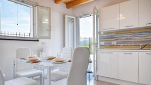 A modern kitchen with white cabinets, a glass dining table, and chairs.