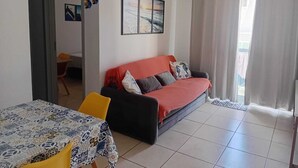 Un salon avec un canapé, une table et un tableau accroché au mur.